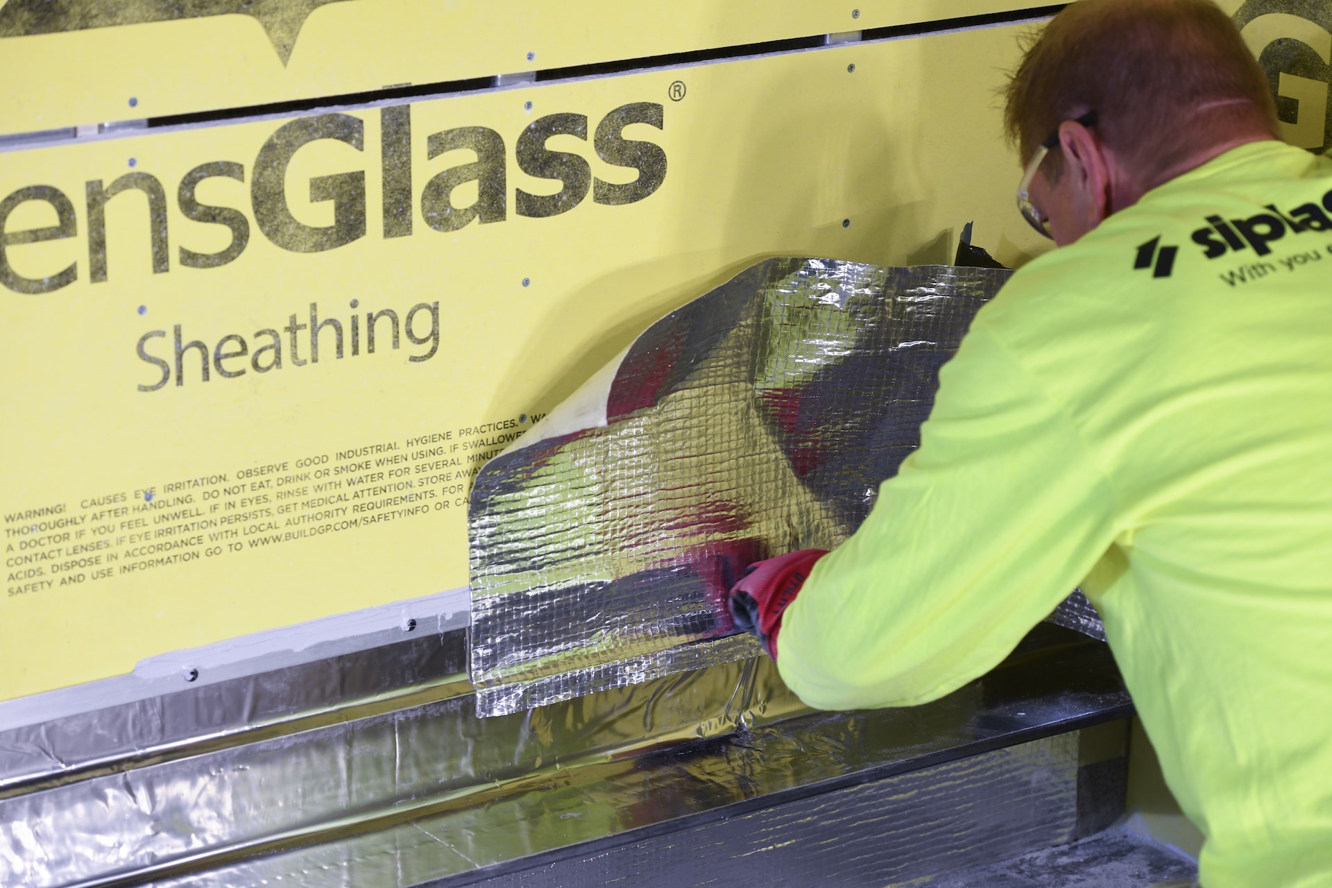 Worker in Siplast apparel applying a self-adhered flashing membrane to act as an air barrier.